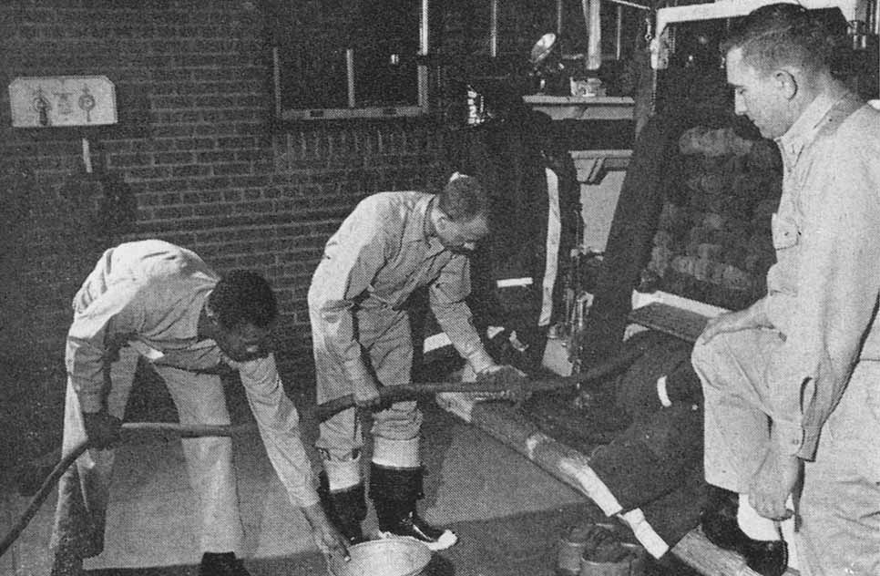 Men in uniform working on a machine.